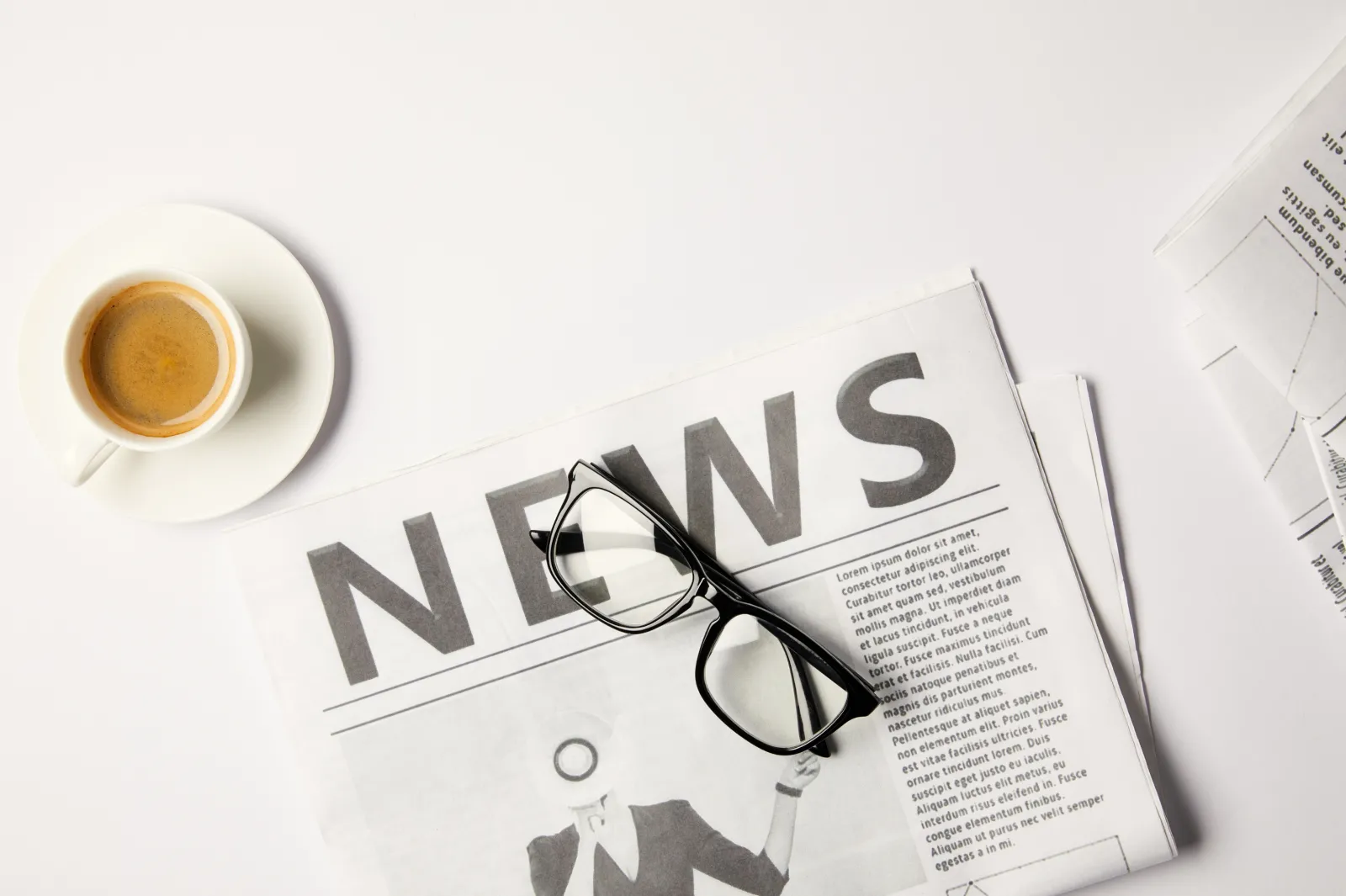 image of a newsletter with glasses on top sitting on a table and a cup of coffee