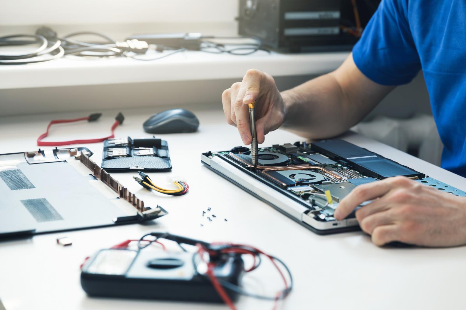 male in a blue shirt fixing a computer