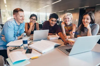 student collaberating at a table in front of a computer