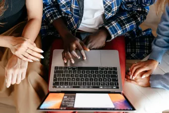 group of 3 people sitting around using a laptop