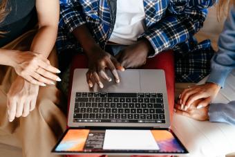 group of 3 people sitting around using a laptop