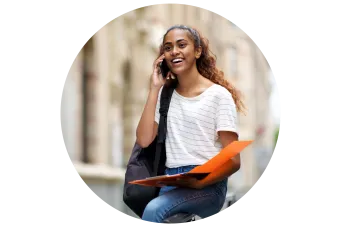 female sitting on hand rail outside while on the phone