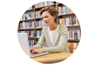 female sitting at a desk while on a computer in the library