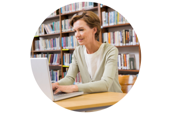 female sitting at a desk while on a computer in the library