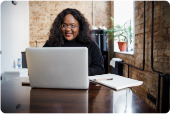 A person sitting at a table in front of a computer working.