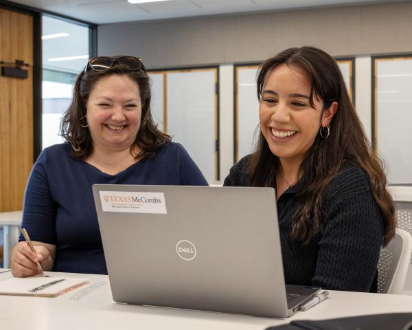 Image of 2 people smiling and working on a laptop
