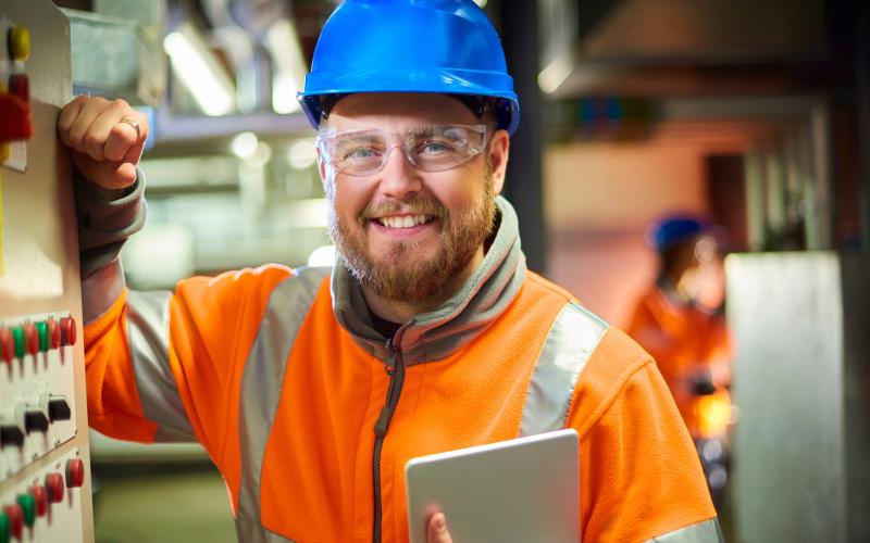 operations employee with hard hat and reflective vest with Ipad