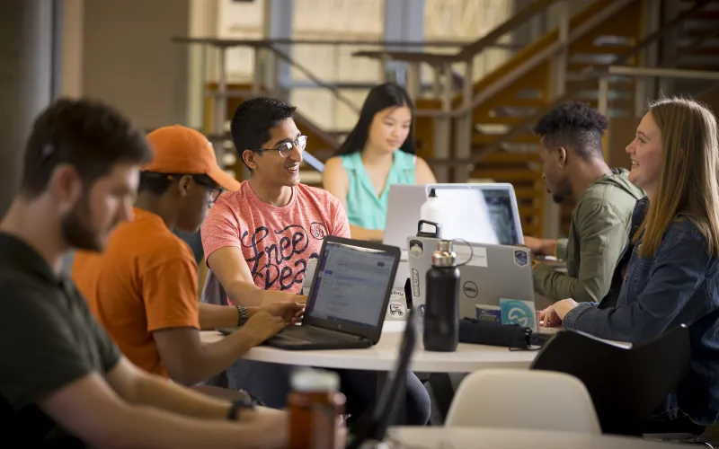 UT students working on laptops conversating