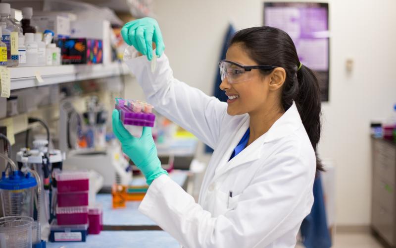 A person in a research lab measuring liquid.